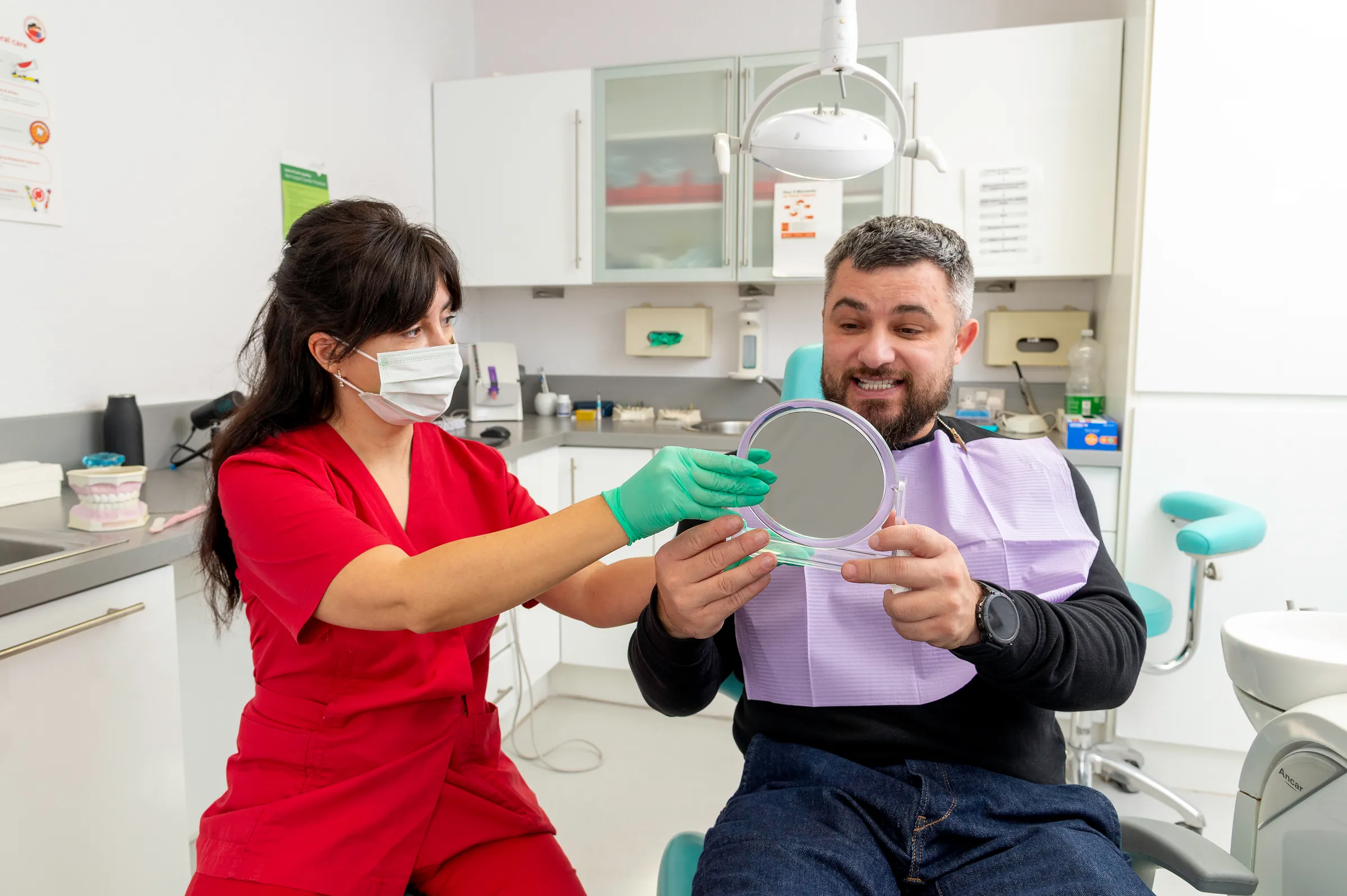 Dr Gianina Kui showing a smiling patient his teeth in a hand mirror