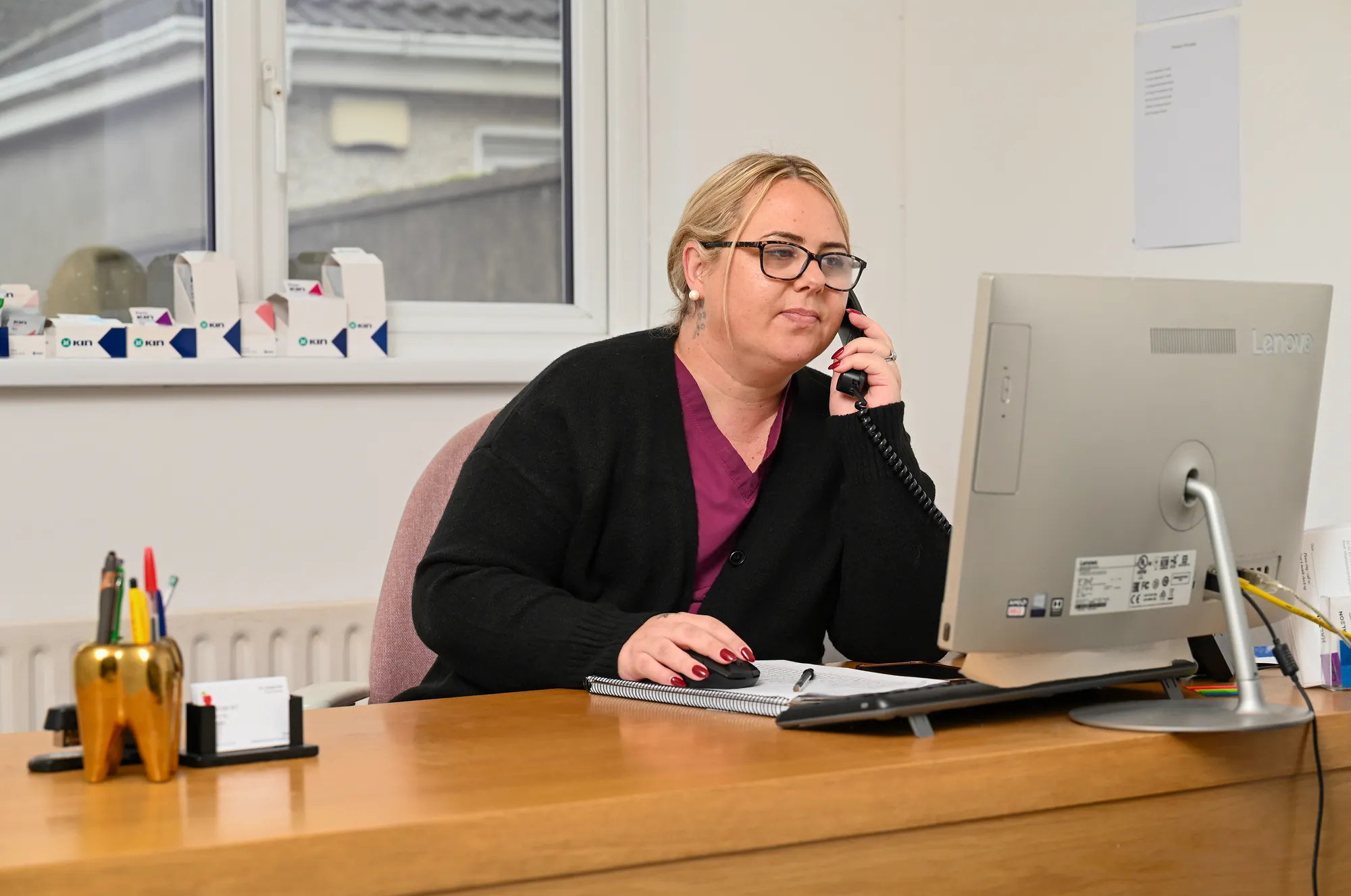 Shirley at the Aylesbury Dental reception desk, on the phone